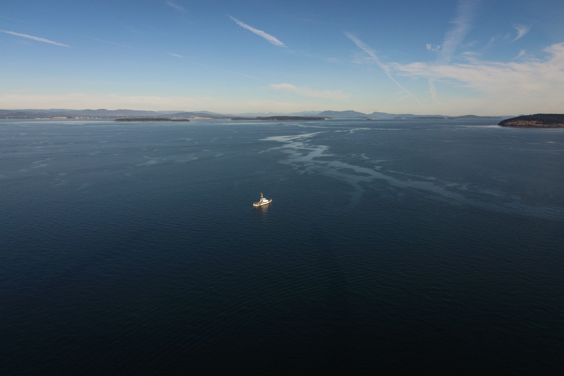 A coast guard vessel with diesel contaminated water with Islands in the distance.